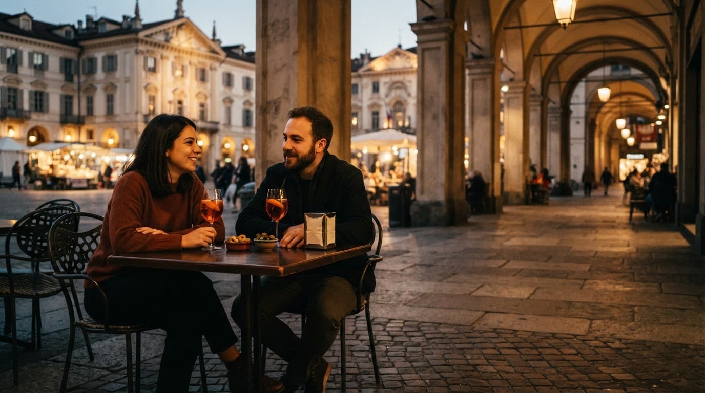 Two people share drinks at an outdoor cafe in a warmly lit Turin piazza.