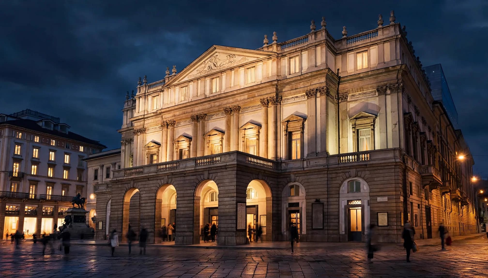 Teatro alla Scala glows warmly over the piazza as people pass at night.