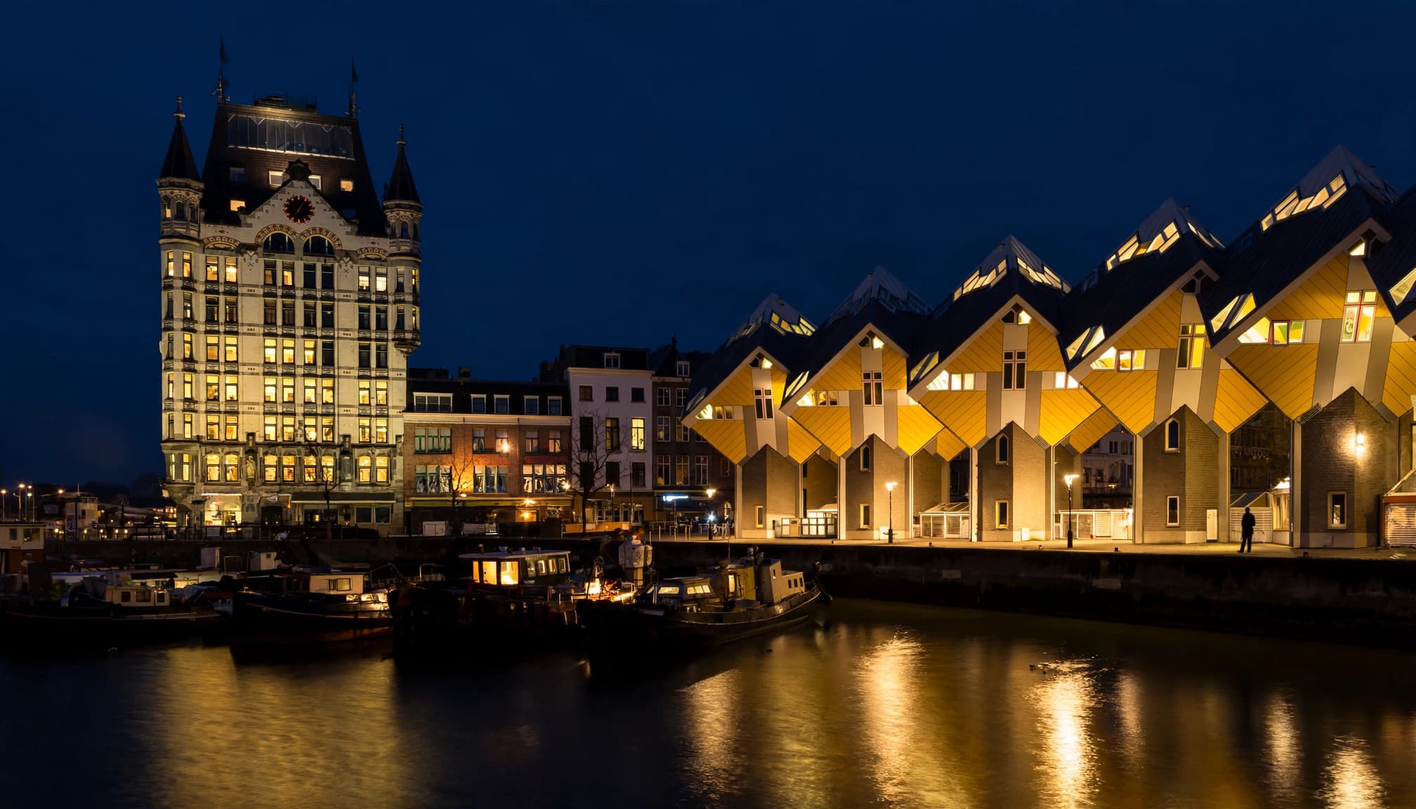 Rotterdam's Oudehaven harbor at night with glowing buildings reflected in dark water.